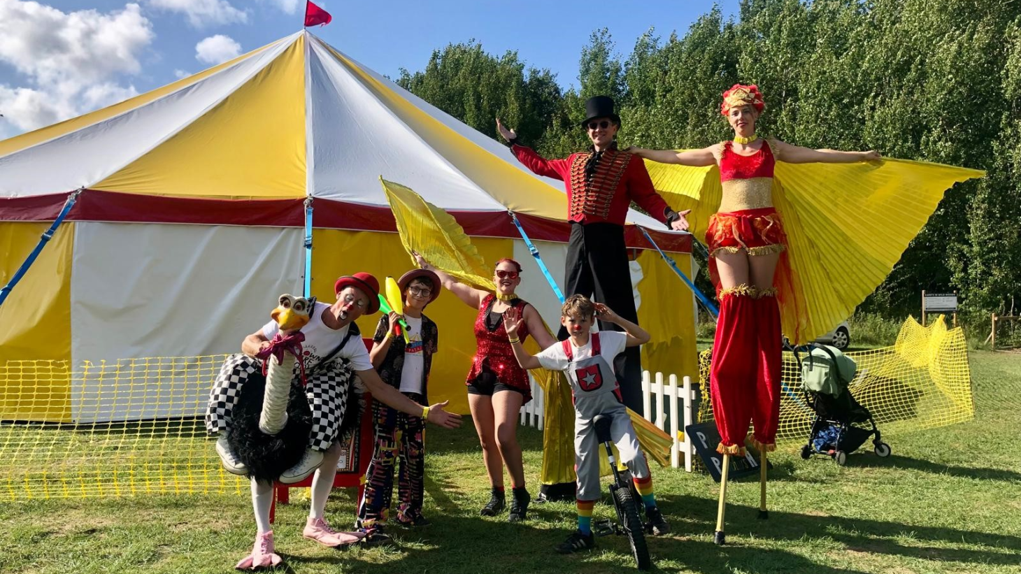 Circus entertainers in front of a big top tent.