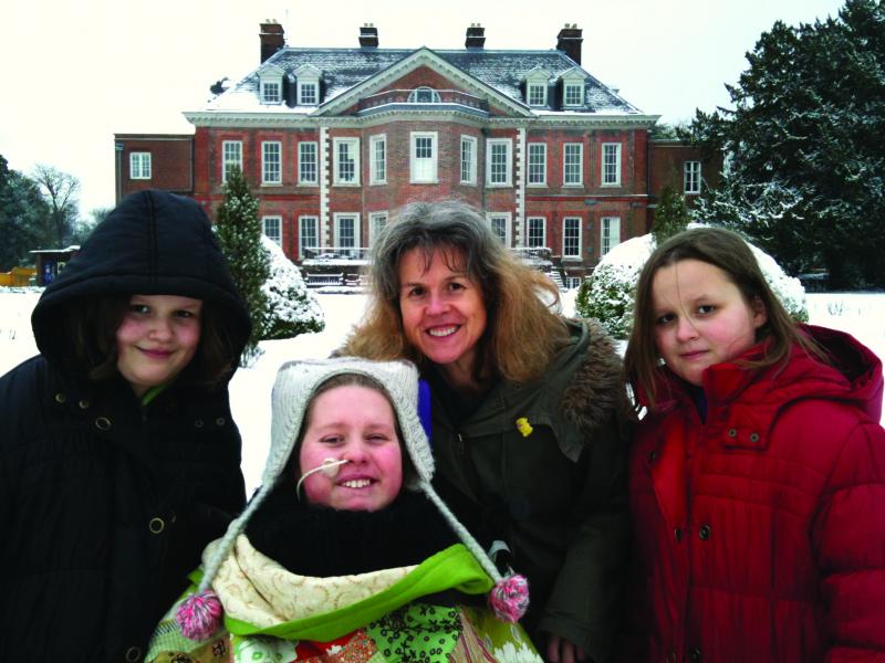 Clare and family in front of The Children's Trust Mansion